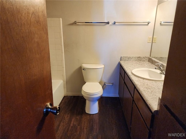 full bathroom with baseboards, toilet, wood finished floors,  shower combination, and vanity