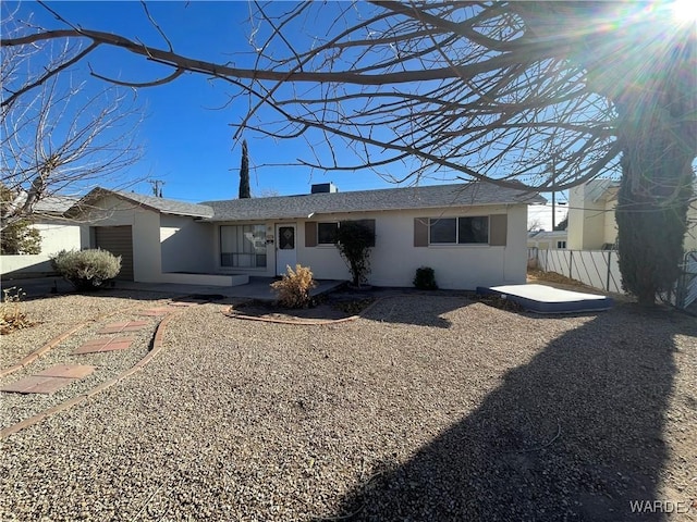 exterior space featuring a garage, a patio area, fence, and stucco siding