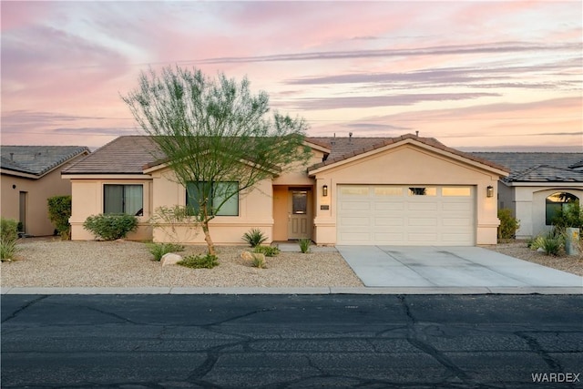 view of front facade with an attached garage, a tiled roof, concrete driveway, and stucco siding