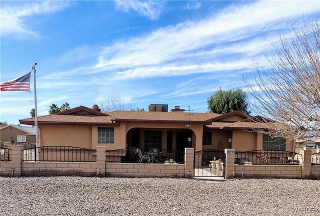 ranch-style home with a fenced front yard, a gate, and stucco siding