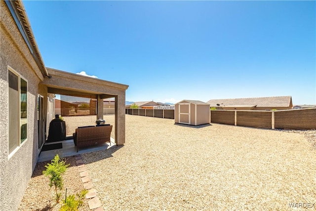 view of yard with a fenced backyard, an outbuilding, a patio area, and a shed