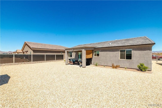 rear view of house featuring stucco siding, a patio area, and fence