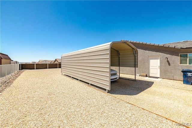 view of property exterior with fence, a detached carport, and stucco siding