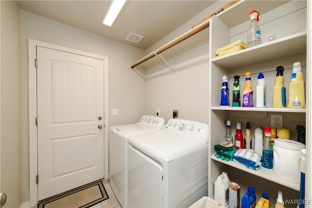 clothes washing area with laundry area, visible vents, and washer and clothes dryer