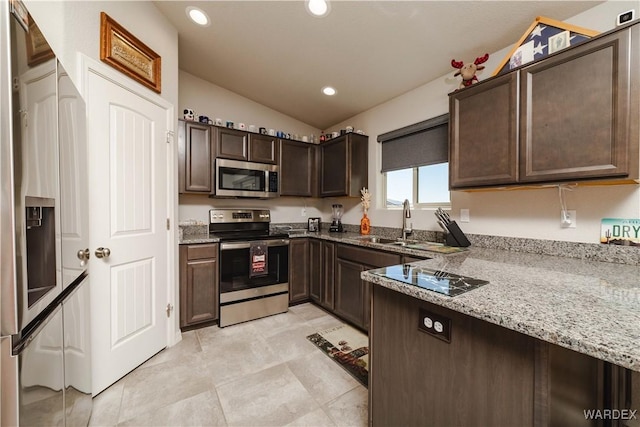 kitchen with dark brown cabinetry, appliances with stainless steel finishes, light stone countertops, a sink, and lofted ceiling