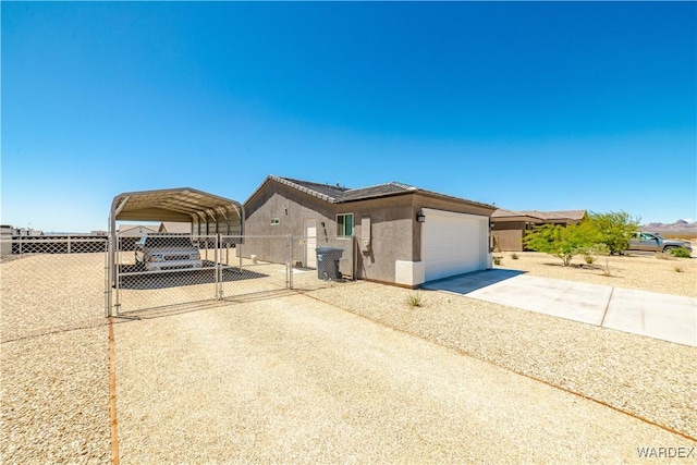 view of front of property featuring a garage, a detached carport, fence, stucco siding, and driveway