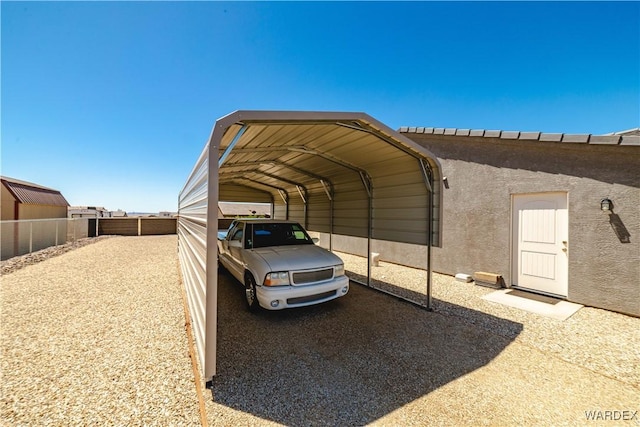 view of vehicle parking with fence and a carport