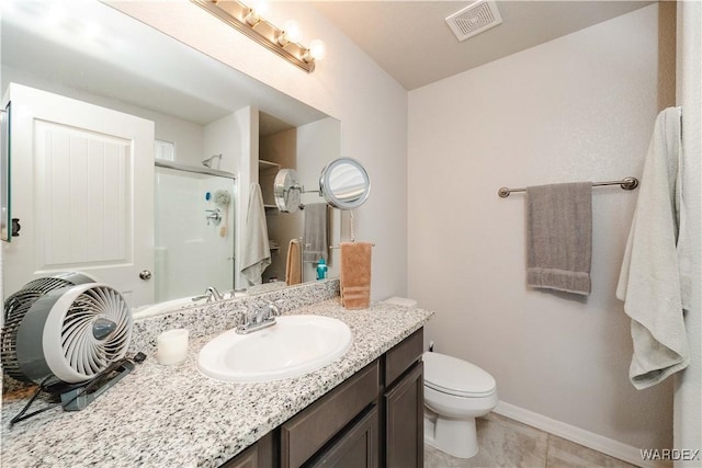 bathroom with visible vents, vanity, toilet, baseboards, and a stall shower