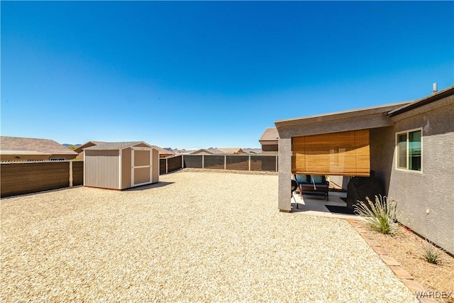 view of yard featuring a fenced backyard, an outdoor structure, a patio area, and a shed