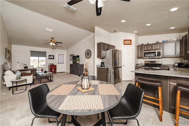 dining area featuring ceiling fan, vaulted ceiling, a textured ceiling, and visible vents