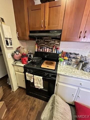 kitchen with dark wood finished floors, light stone counters, black gas range oven, and under cabinet range hood