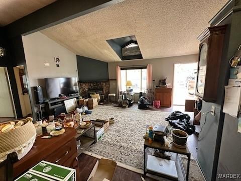 living room featuring lofted ceiling with beams, a fireplace, and a textured ceiling