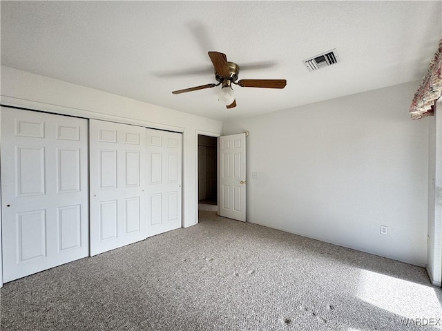 unfurnished bedroom featuring carpet floors, a closet, visible vents, and a ceiling fan