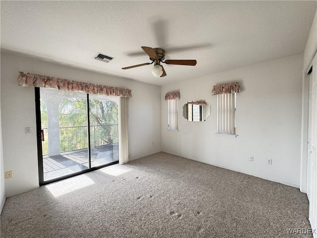 carpeted empty room featuring visible vents, ceiling fan, and a textured ceiling