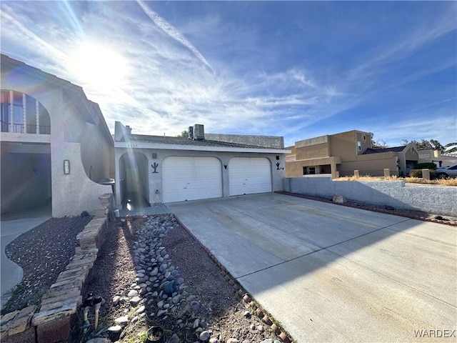 exterior space featuring a garage, concrete driveway, central AC, and stucco siding