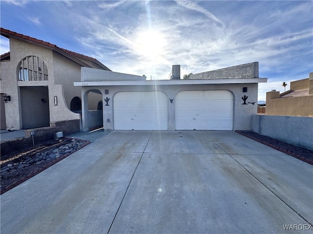 view of front of home with an attached garage, fence, concrete driveway, and stucco siding