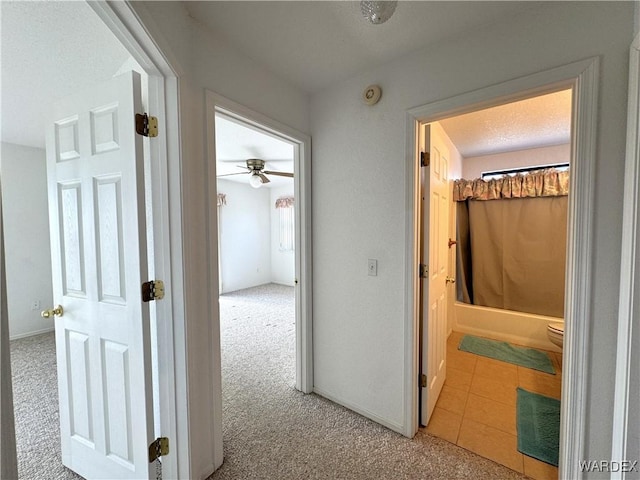 corridor featuring light colored carpet, baseboards, and light tile patterned floors