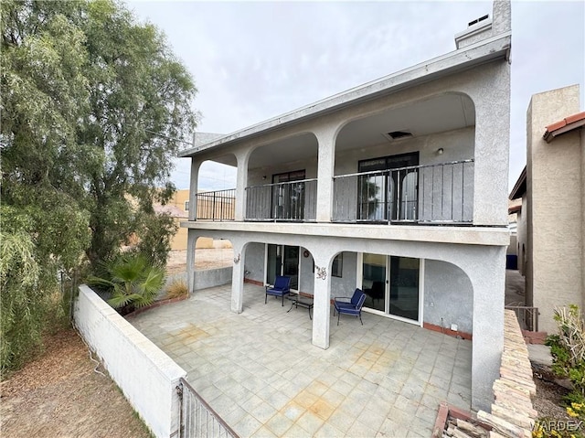 back of house featuring a patio area, a balcony, and stucco siding