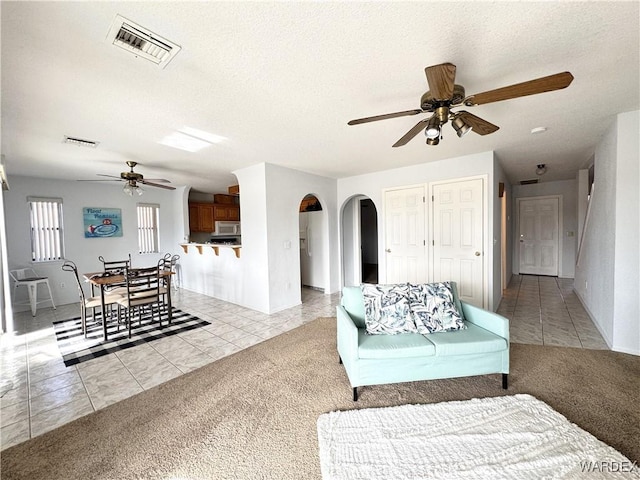 living room featuring light colored carpet, visible vents, and light tile patterned floors