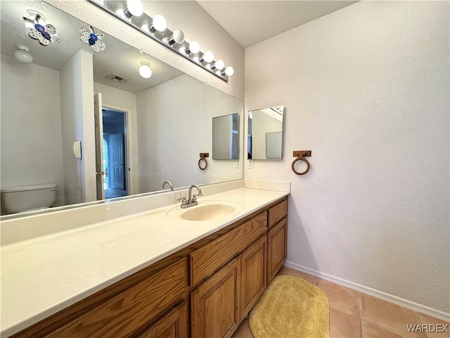 bathroom with visible vents, toilet, vanity, baseboards, and tile patterned floors