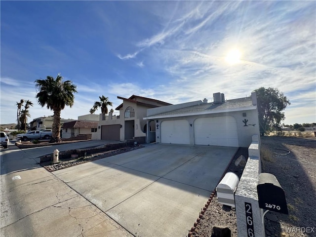 view of front of home with a garage, concrete driveway, and stucco siding