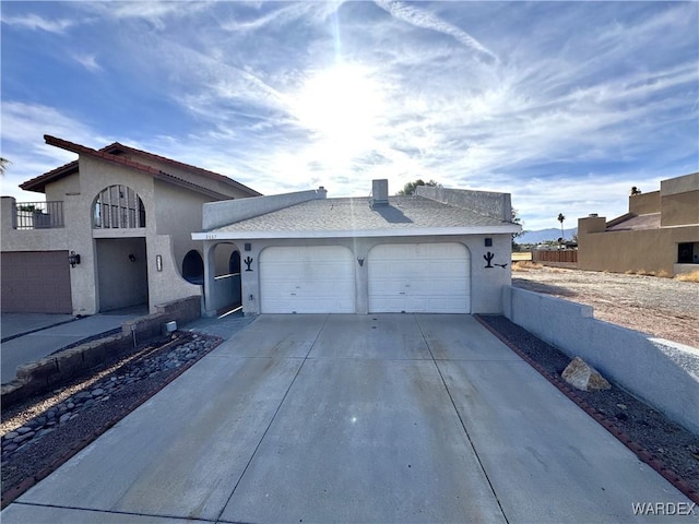 view of front of property with driveway, an attached garage, fence, and stucco siding