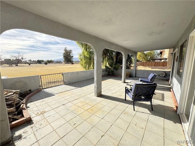 view of patio featuring a rural view and fence