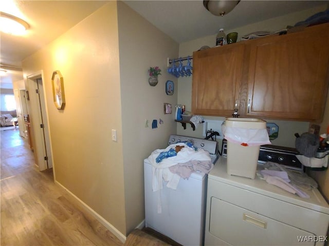 laundry area with cabinet space, light wood-style flooring, baseboards, and washing machine and dryer