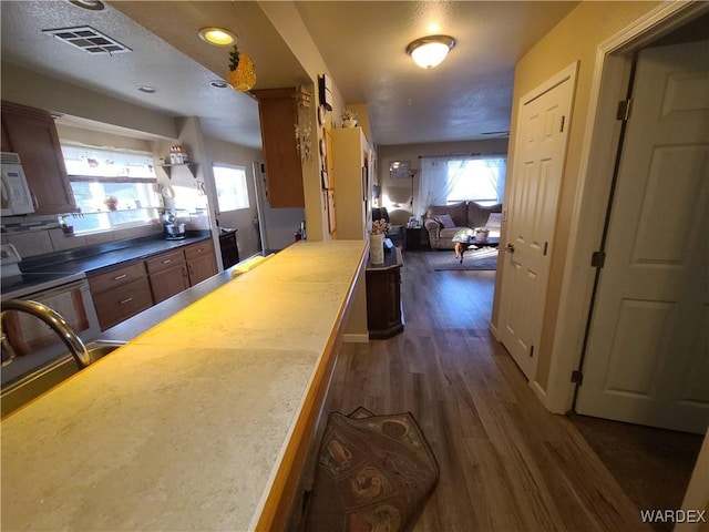 kitchen featuring a wealth of natural light, light countertops, visible vents, and dark wood finished floors