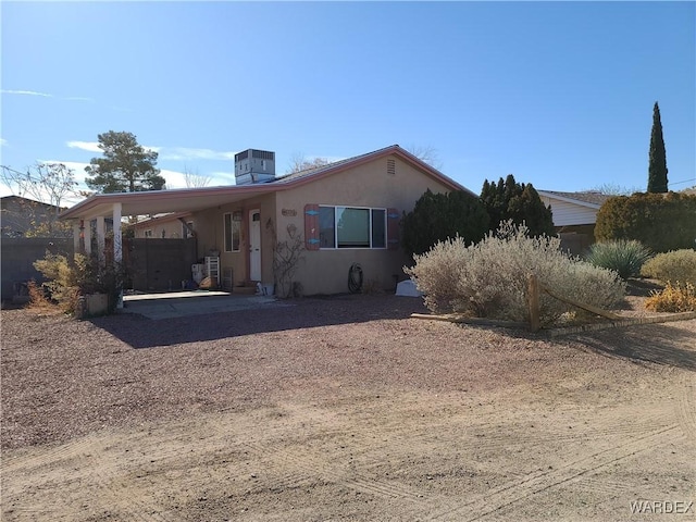 view of front of home with a carport, central air condition unit, driveway, and stucco siding