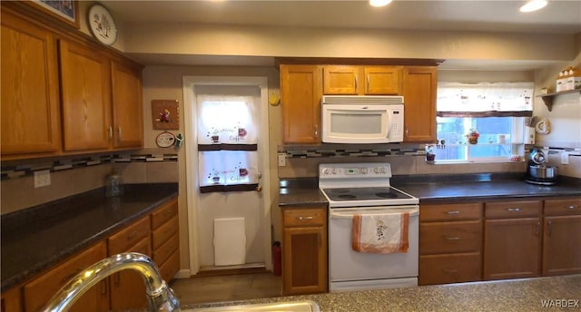 kitchen with white appliances, tasteful backsplash, brown cabinetry, dark countertops, and a wealth of natural light