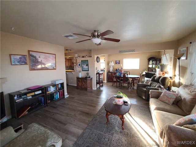 living room featuring a ceiling fan, visible vents, and dark wood-style flooring