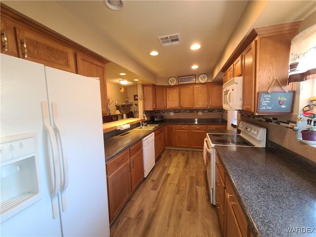 kitchen with white appliances, a sink, visible vents, light wood-style floors, and dark countertops