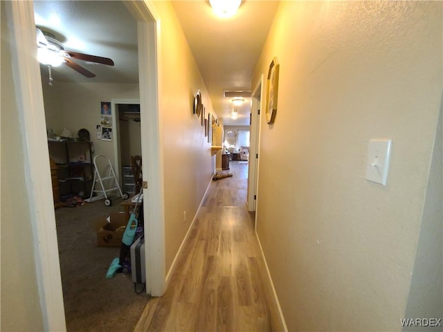 corridor featuring light wood finished floors and baseboards