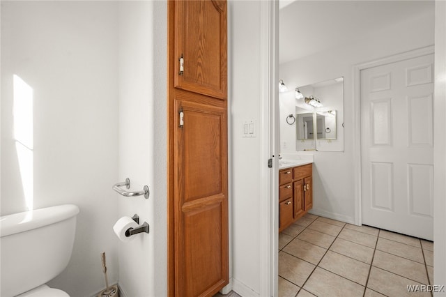 bathroom with toilet, tile patterned flooring, vanity, and baseboards