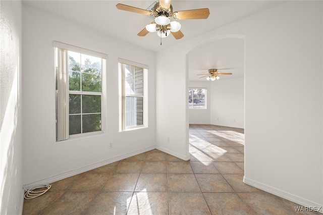 unfurnished room featuring ceiling fan, baseboards, and light tile patterned floors