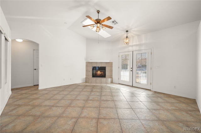 unfurnished living room with french doors, a fireplace, visible vents, a ceiling fan, and vaulted ceiling