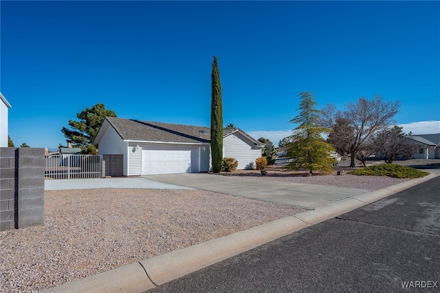 view of front of house featuring a garage, concrete driveway, and fence