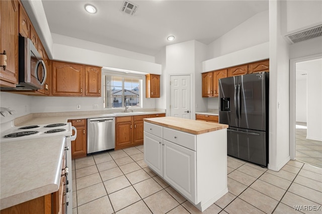 kitchen with visible vents, a kitchen island, appliances with stainless steel finishes, and brown cabinetry