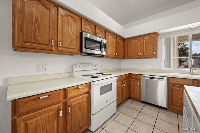 kitchen with light tile patterned floors, light countertops, appliances with stainless steel finishes, brown cabinetry, and a sink