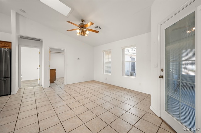 unfurnished room with lofted ceiling with skylight, visible vents, a ceiling fan, and light tile patterned flooring