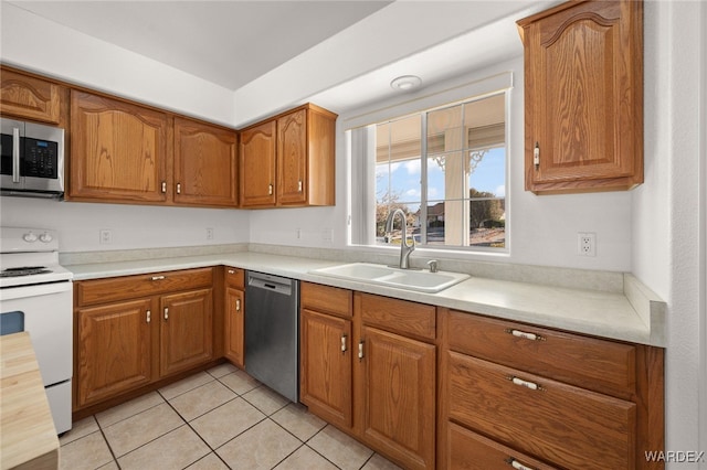 kitchen with brown cabinetry, appliances with stainless steel finishes, light countertops, and a sink