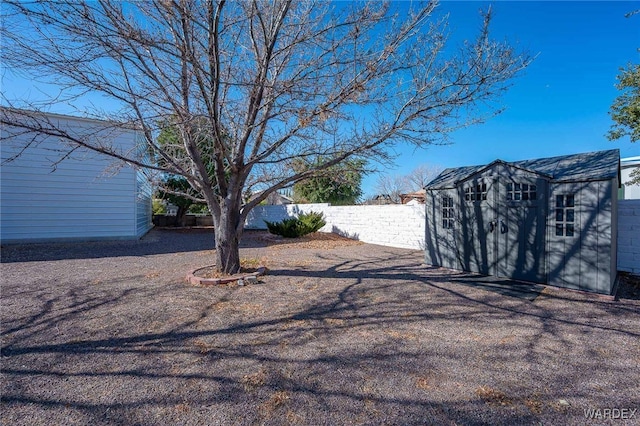 view of yard with a fenced backyard, an outdoor structure, and a storage shed