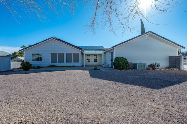 view of front of home featuring a patio, central AC unit, solar panels, and fence