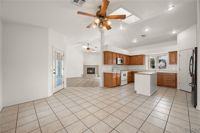 kitchen with a kitchen island, light countertops, freestanding refrigerator, white range with electric stovetop, and stainless steel microwave