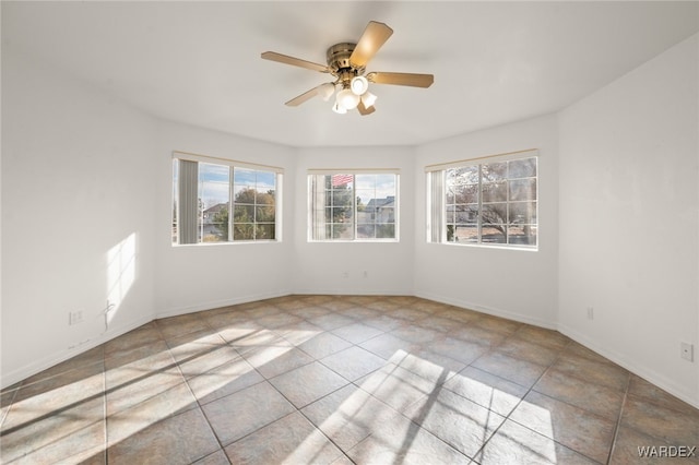 unfurnished room with a ceiling fan and baseboards