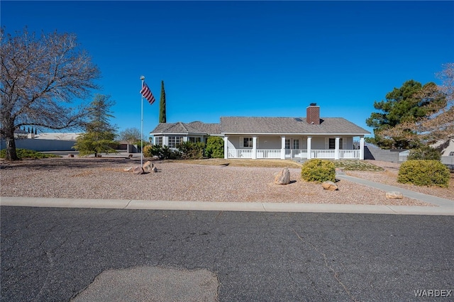 view of front of property with a porch, a chimney, and fence