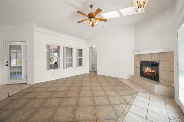 unfurnished living room with a fireplace, vaulted ceiling, a ceiling fan, and tile patterned floors