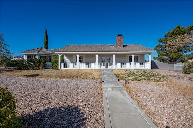 view of front of property featuring covered porch, a chimney, and fence