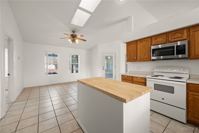 kitchen with electric stove, brown cabinets, stainless steel microwave, a kitchen island, and wood counters